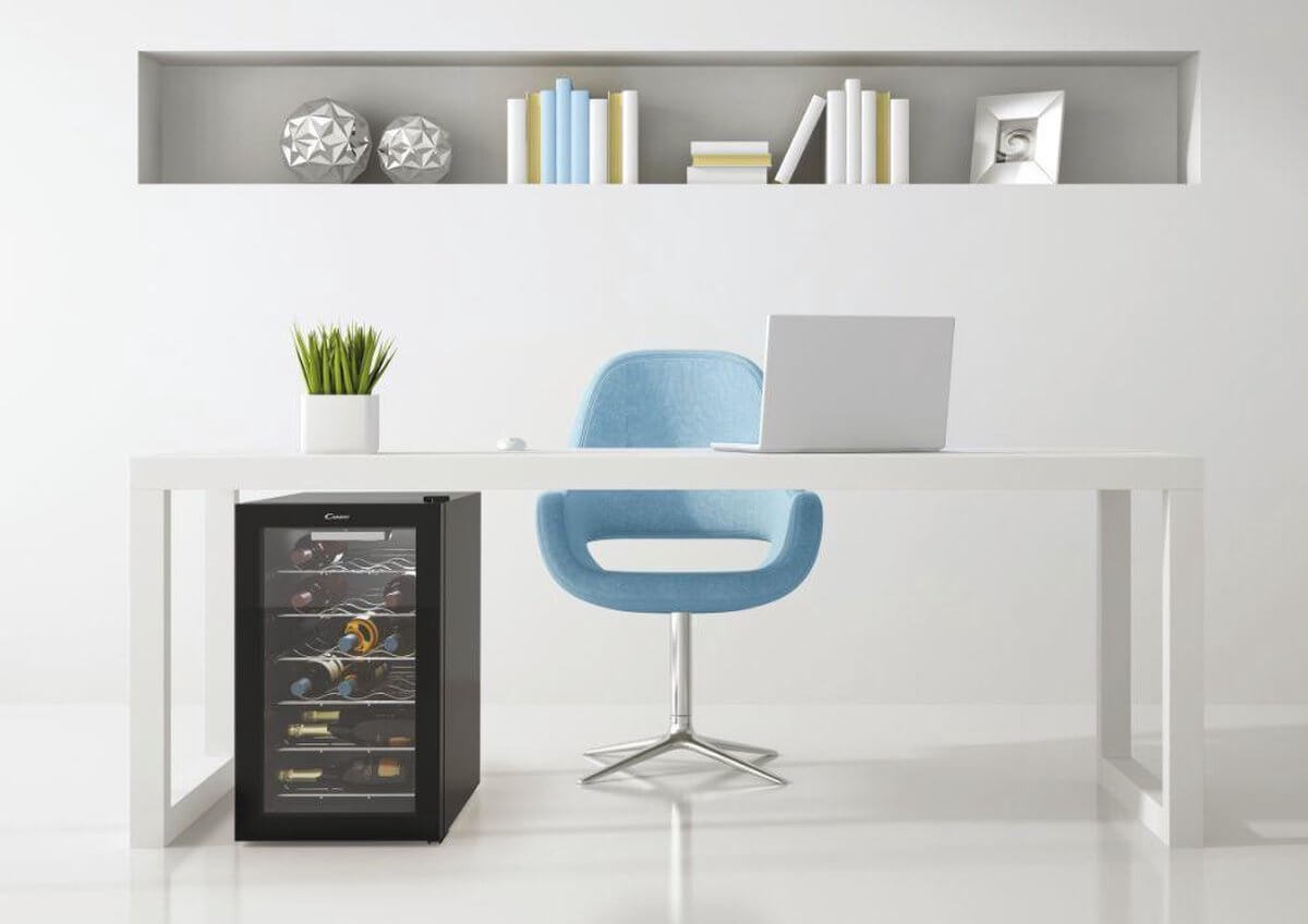 Candy CWC 021 M/N wijnkoelkast onder een modern wit bureau met blauwe designstoel in minimalistisch interieur, geschikt voor 21 flessen