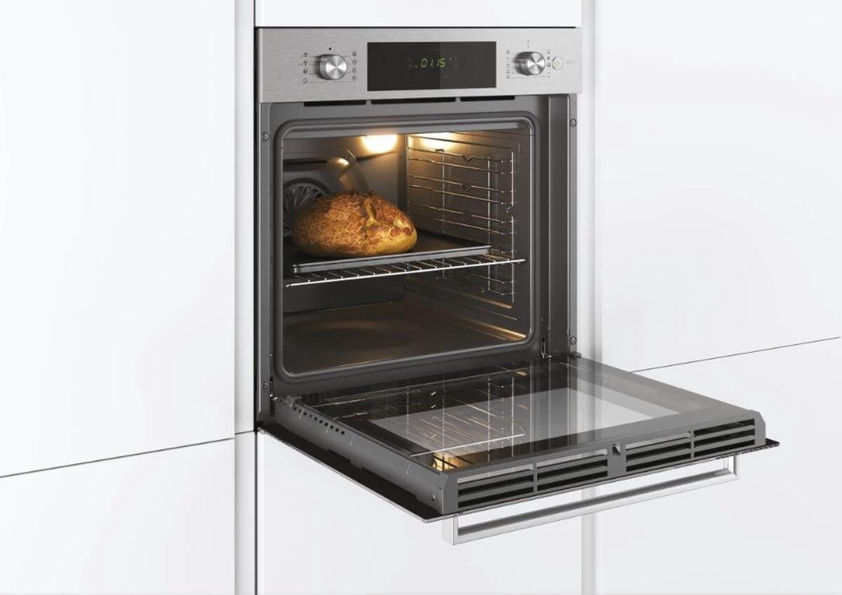 Candy FCTS886X oven ingebouwd in een keuken, met een brood in de oven tijdens het bakken.