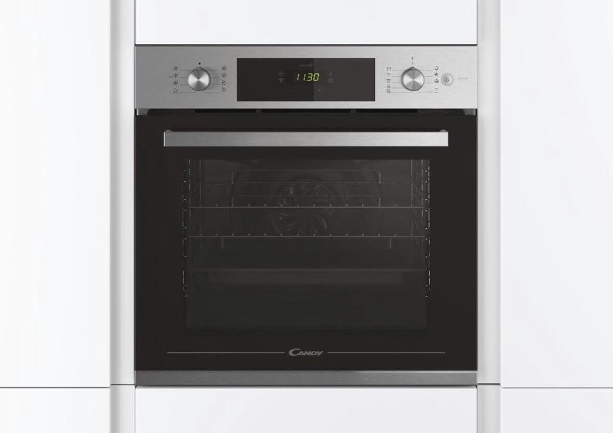 Candy FCTS886X oven ingebouwd in een moderne witte keuken, met gesloten deur.
