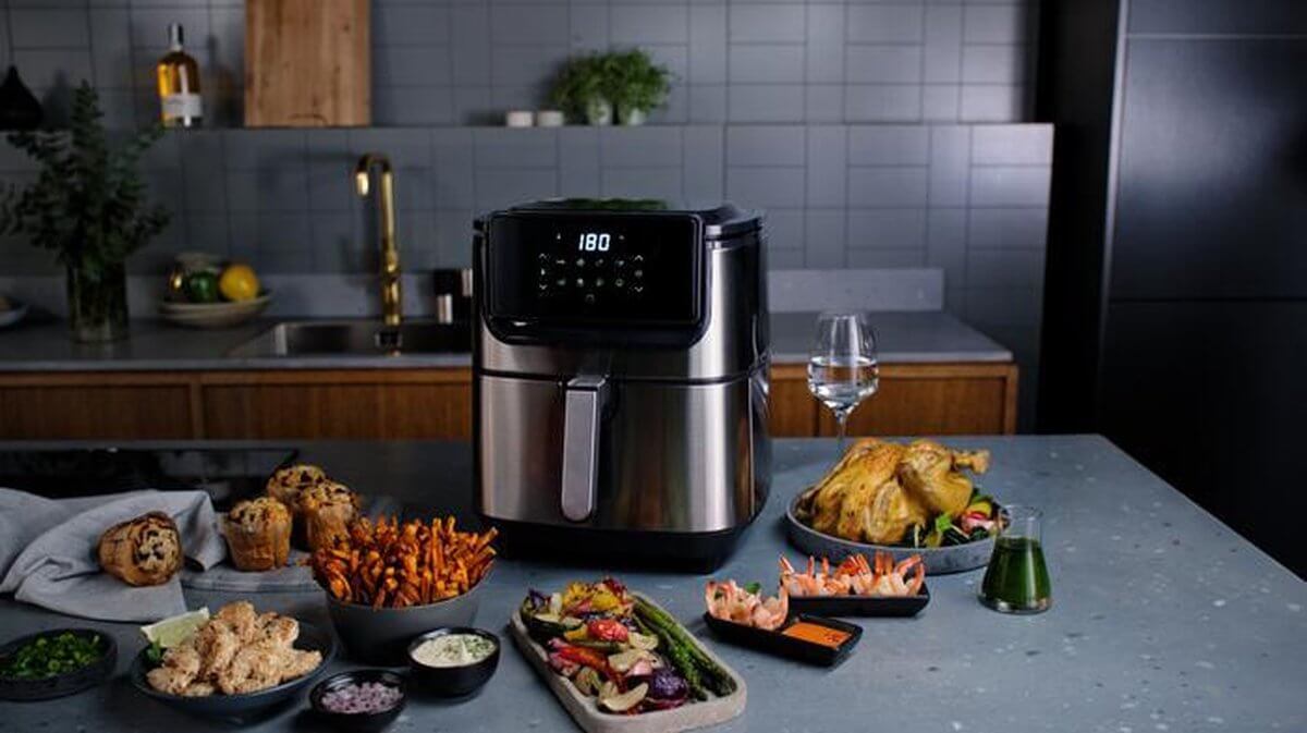 Electrolux E6AF1-4ST airfryer in keukenopstelling met luxe maaltijdpresentatie waaronder gegrilde kip, groenten en garnalen.